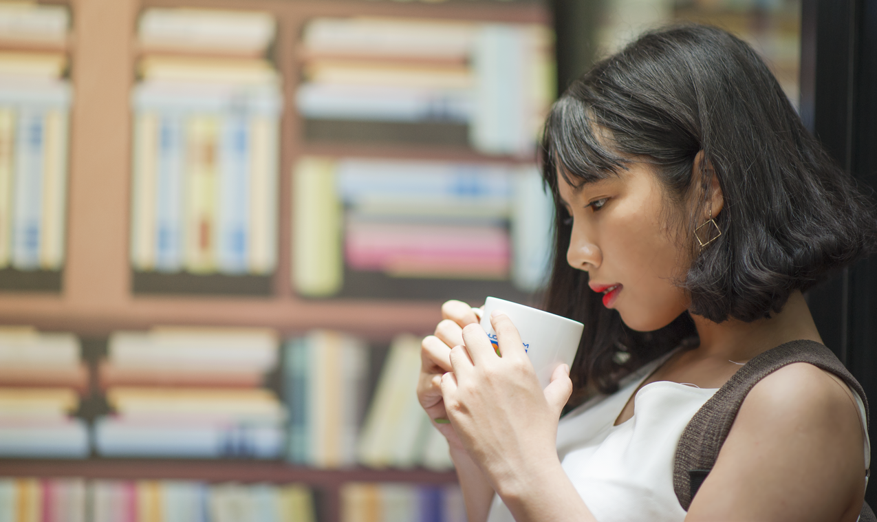 一个女人拿着白色咖啡杯的高清图片