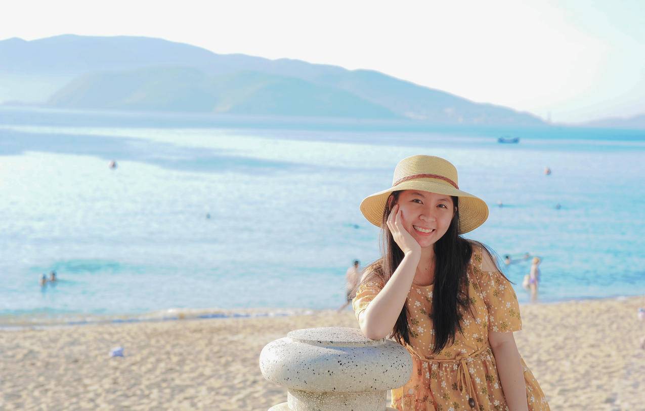 海滩上穿着黄色花衣和太阳帽的女人