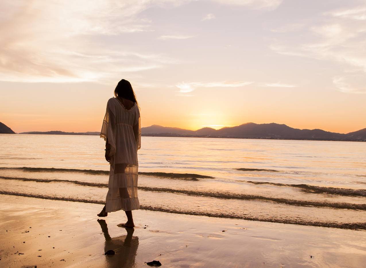 穿着白色连衣裙的女人在Beach漫步