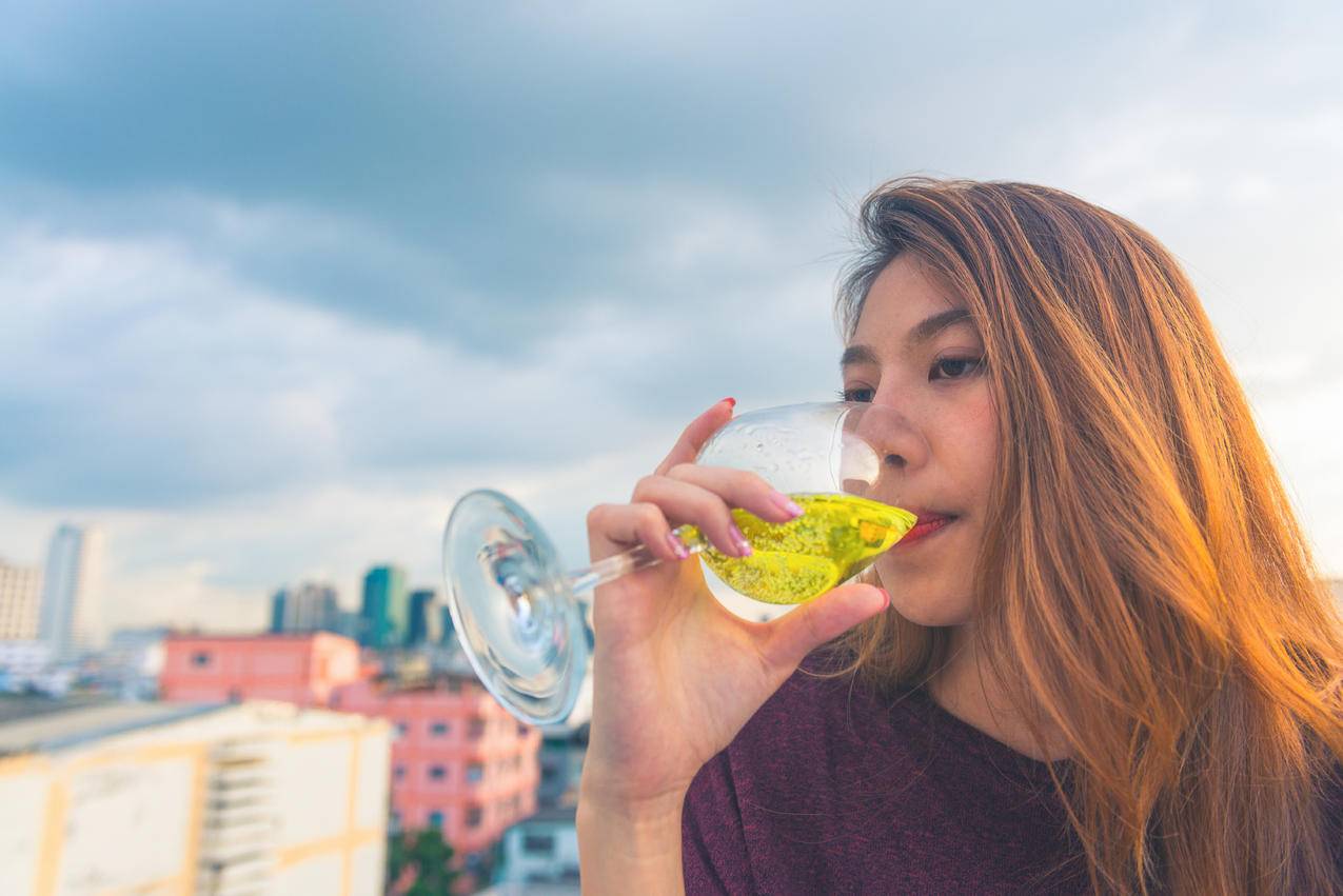 紫色的女人在清澈的酒杯上喝酒