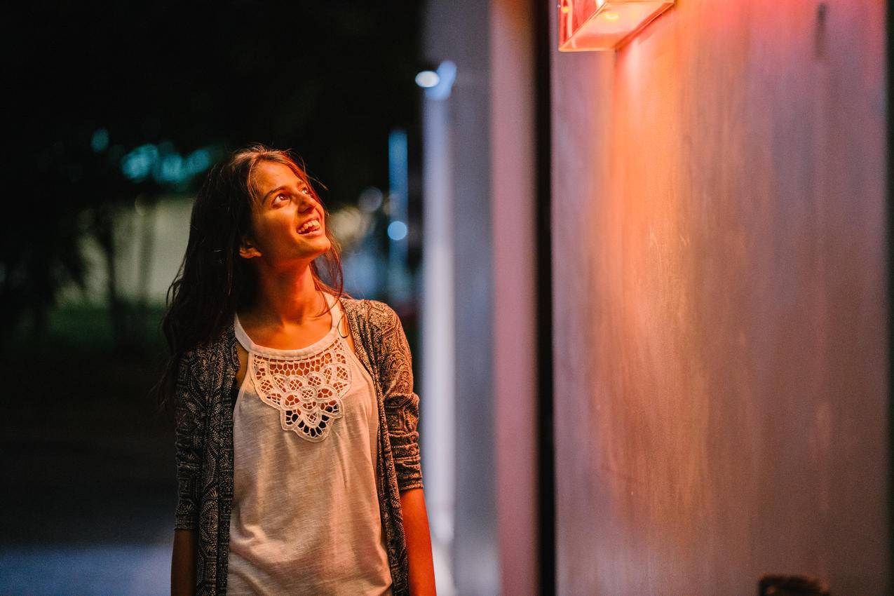 穿着灰色开衫的女人在夜间站在墙边