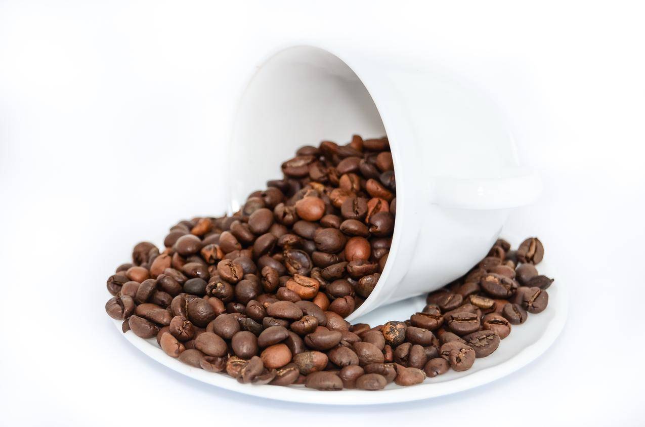 白色陶瓷杯和盘子上的咖啡豆