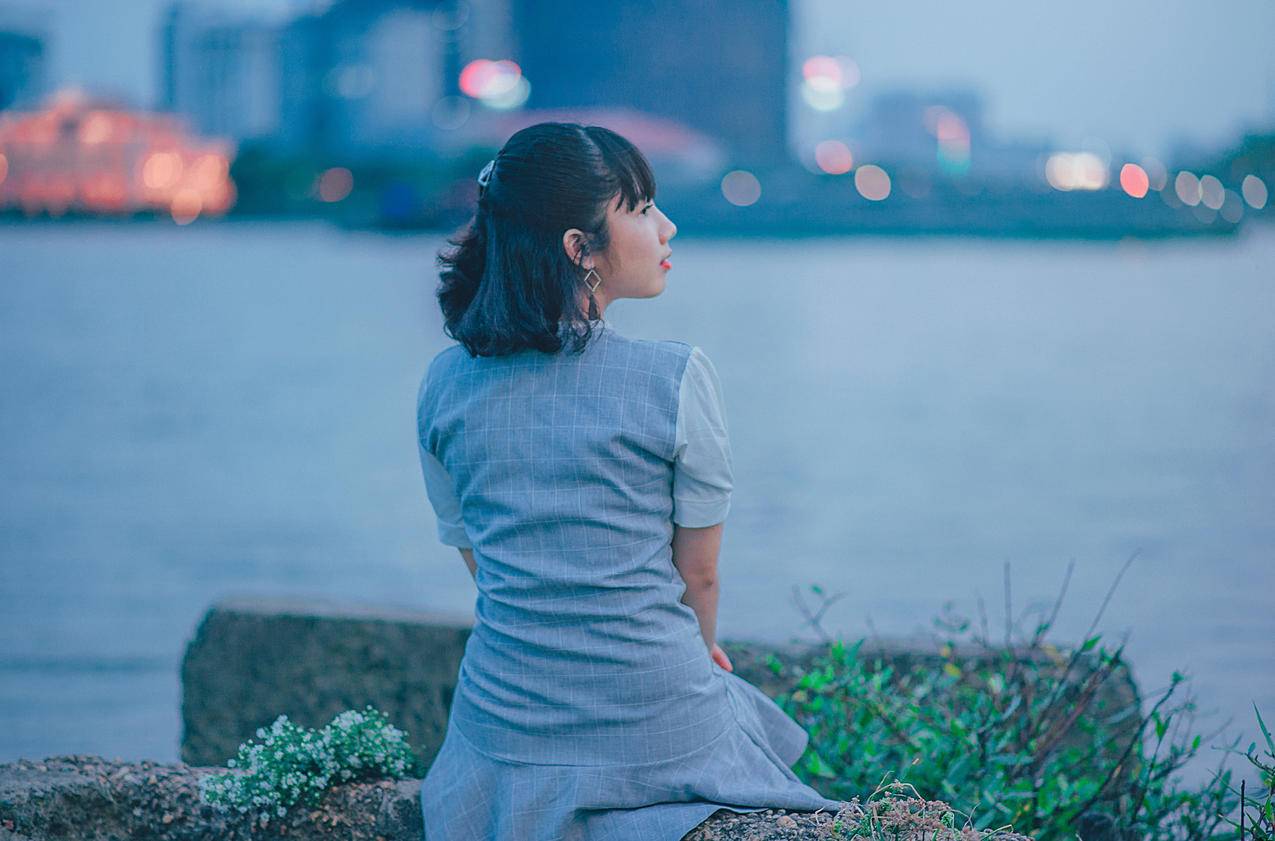 穿着灰色衣服的女人坐在靠近水的地方