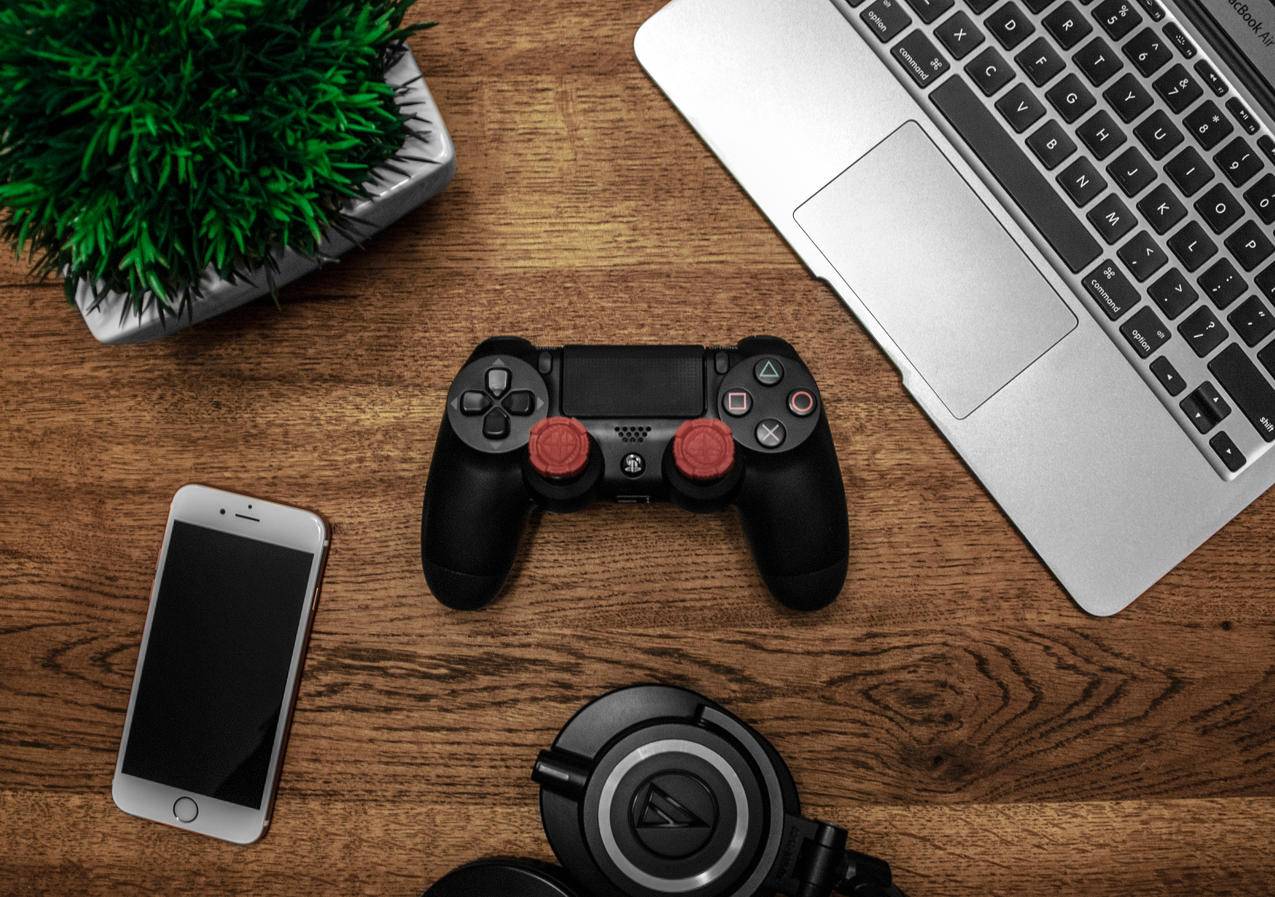 黑色MacBook旁边的黑色索尼PS4,DualS休克4,银iPhone,6,和黑色黑色钥匙扣在棕色木桌上